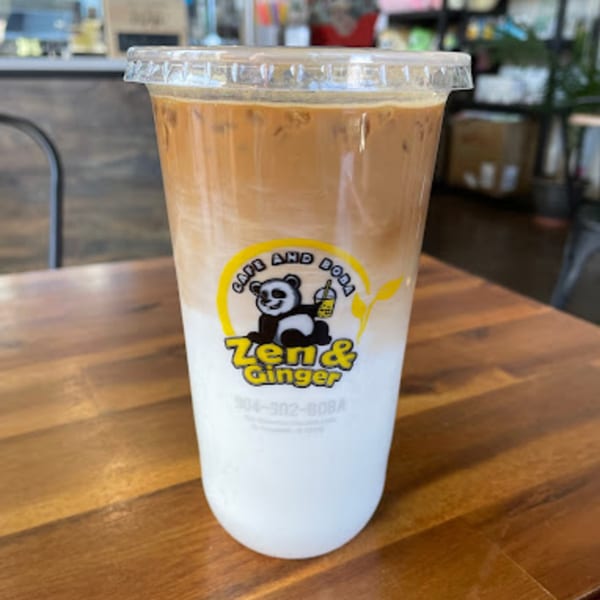 Iced Vietnamese coffee with milk, featuring the Zen & Ginger logo, on a wooden table.
